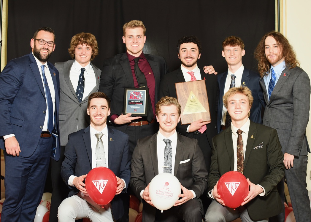 Eight TKE Duluth brothers holding their Top TKE Chapter and 100% KRA award plaques with TKE and St. Jude balloons at the St. Jude Gala