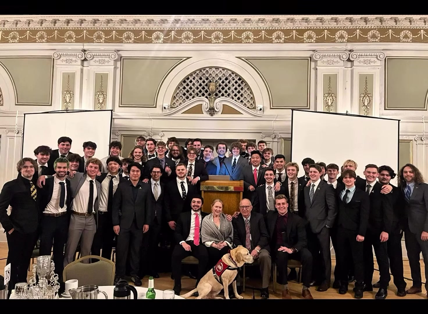 A brother speaking at the podium under the ballroom arch